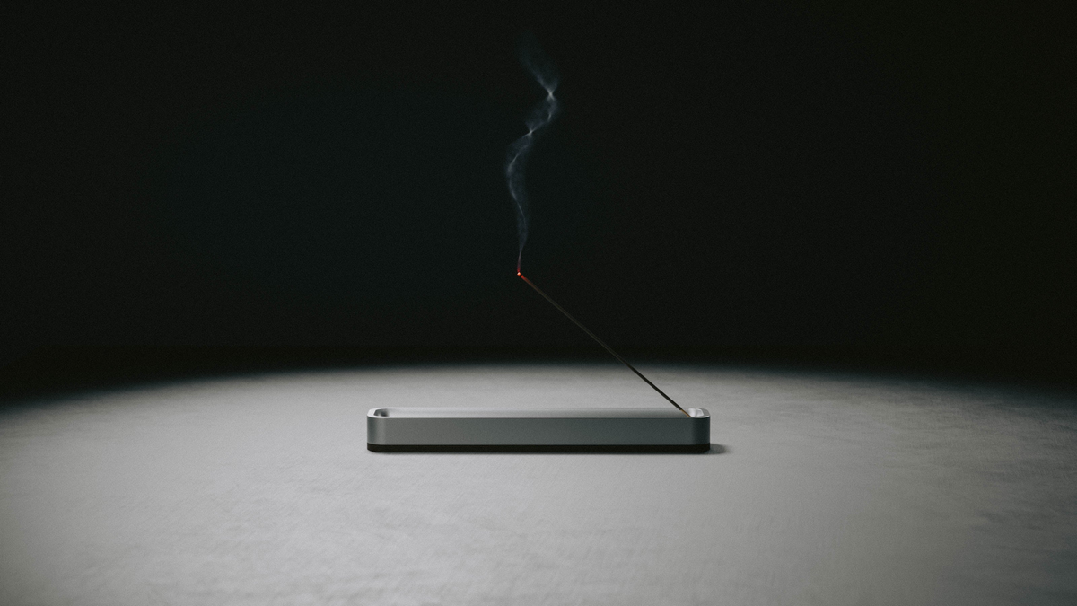 Incense Holder with a lit stick under a single spotlight